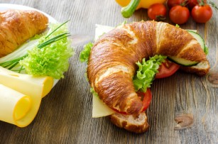 Croissant sandwich with cheese and vegetables for healthy snack, rustic wooden background