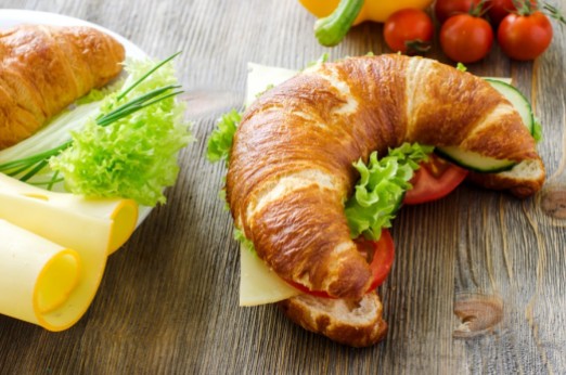 Croissant sandwich with cheese and vegetables for healthy snack, rustic wooden background